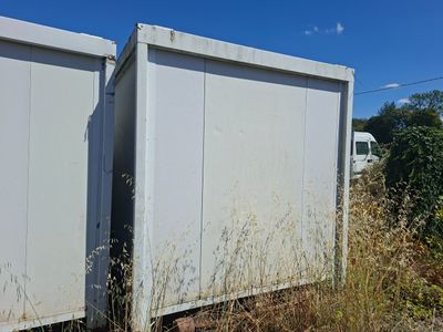 deux conteneurs de stockage blancs posés au milieu d'un champ