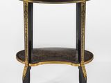 une table d'appoint noire et dorée, surmontée d'un plateau circulaire