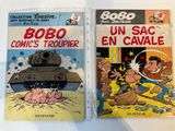 two comics are on display on a table in front of a white background