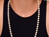 une femme portant un débardeur noir et un collier de perles