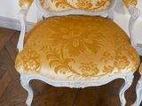 a yellow and white chair and two chairs on a wood floor