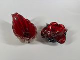two red glass objects sitting on a white surface