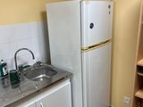 a small kitchen with a refrigerator, sink, and shelves