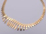 a close up of a gold necklace on a white surface