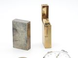 un briquet, une horloge et une pièce de monnaie posés sur une surface blanche