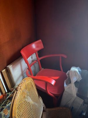 a red chair sitting in a corner of a room next to a window