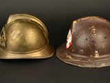 pair of wwii era german steel helmets on a black background