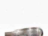 a silver spoon with a handle sitting on top of a white surface
