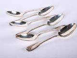 six silver spoons are lined up on a white surface