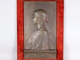 une plaque métallique représentant une femme, dans un cadre rouge sur fond blanc