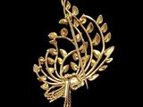 a close up of a gold brooch with a bird on it