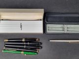 an assortment of pens and a case sitting on a table
