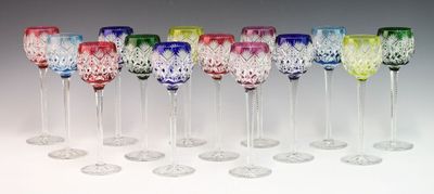 seven colorful wine glasses lined up in a row on a white surface
