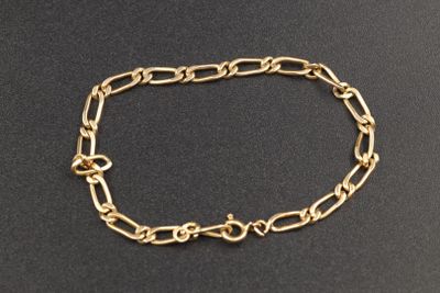 gros plan d'un bracelet en chaîne en or sur une surface noire