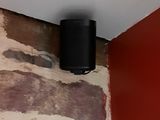 une enceinte noire posée sur un mur de briques dans un coin de la pièce