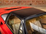 an image of a red sports car parked in front of a brick wall