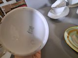 a person holding a bowl on a table with plates and cups