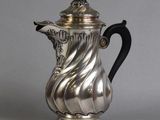 une cafetière en argent avec une poignée noire sur un fond gris