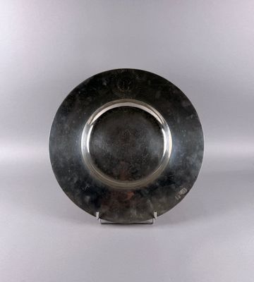 a silver plate on a stand on a white surface