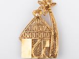 an image of a gold plated house brooch with a bird on top
