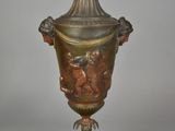 a bronze vase on a wooden stand with a white background
