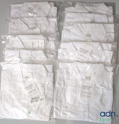 Plusieurs chemises blanches sont emballées dans des sacs en plastique sur une table