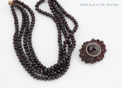 a close up of a necklace and a broochle on a white surface