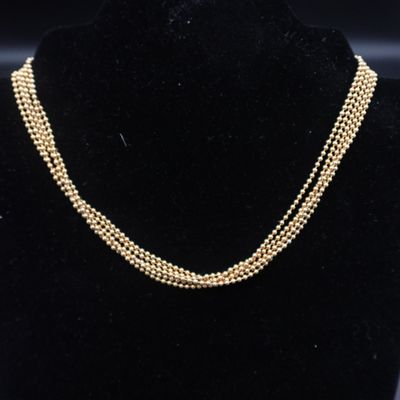 un collier de perles dorées sur un mannequin d'exposition