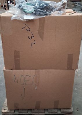 une boîte en carton posée sur une palette, sur laquelle se trouve un tas de vis
