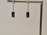 paire de boucles d'oreilles carrées noires et argentées, montées sur un support plaqué or