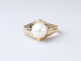 a close up of a gold ring with a pearl in it