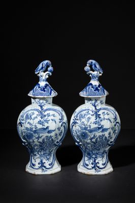 pair of blue and white vases with figures on top of them