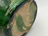 a close up of a green vase on a white surface