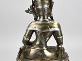 a silver statue of a buddha sitting on top of a table