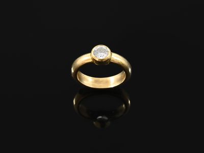 a gold ring with a single diamond on a black surface