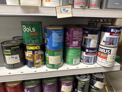 de nombreux pots de peinture sur une étagère dans un magasin