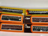 six model trains in boxes sitting on a white surface