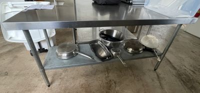 a stainless steel table with pots and pans on it