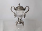an antique silver plated trophy sitting on top of a glass table