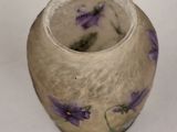 a small vase with purple flowers in it on a white surface