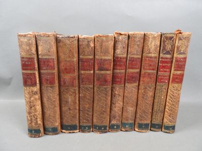 six old books are lined up in a row on a white surface