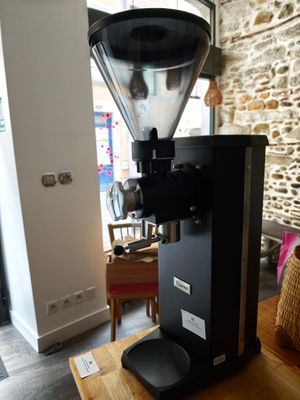 un moulin à café posé sur une table devant un mur en pierre