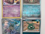 Quatre cartes Pokémon différentes sont posées sur une table avec un fond blanc.