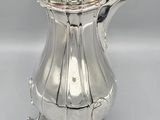 a silver coffee pot with a lid on a stand