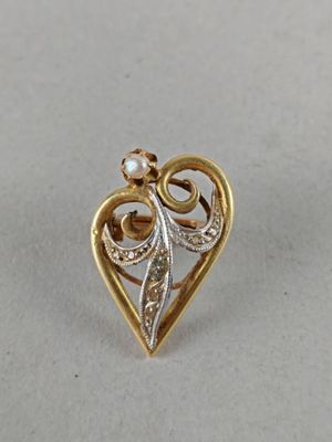 a close up of a gold and diamond heart brooch