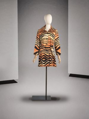 une robe orange et noire posée sur un mannequin dans une pièce