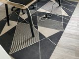 un tapis noir et blanc posé au sol, sur lequel se trouve un ordinateur portable