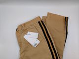 Le pantalon est de couleur beige avec des rayures noires et une étiquette.