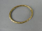 gros plan d'un bracelet en or sur une surface blanche