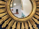 a gold sunburst mirror hanging on the wall